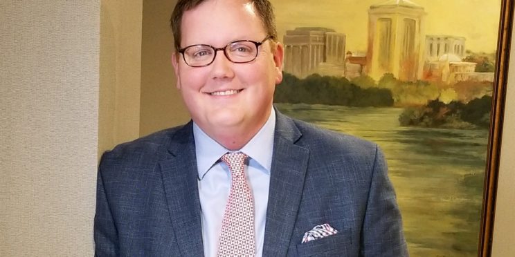 Jason Isbell poses in a suit and is leaning against a wall.
